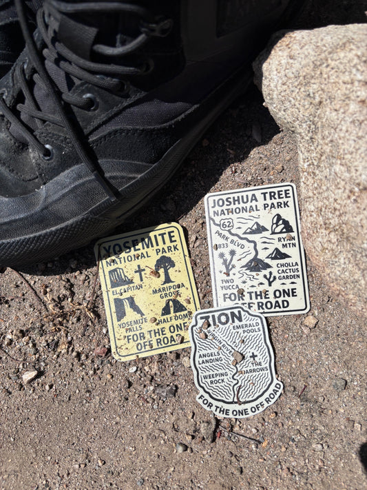 National Park stickers on a textured surface with a shoe in the foreground.