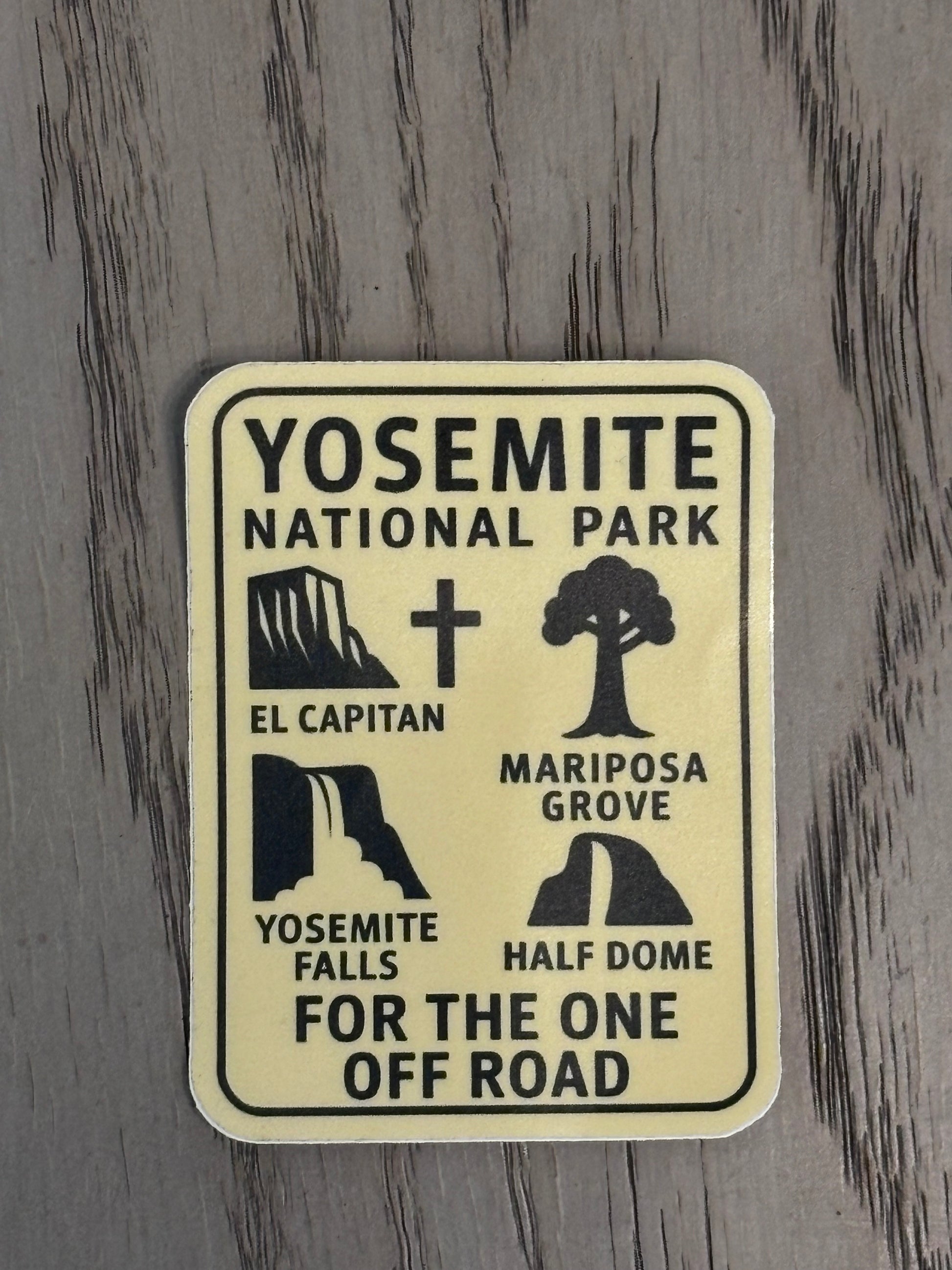 Yosemite National Park sticker with black text and icons on a beige background, placed on a textured gray surface.